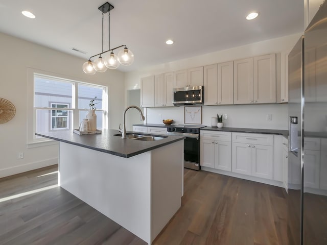 kitchen featuring dark wood-style flooring, visible vents, a sink, dark countertops, and appliances with stainless steel finishes