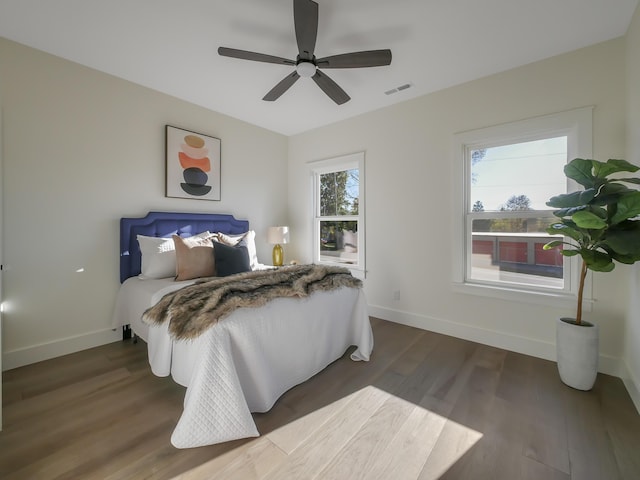 bedroom featuring dark wood finished floors, visible vents, baseboards, and a ceiling fan