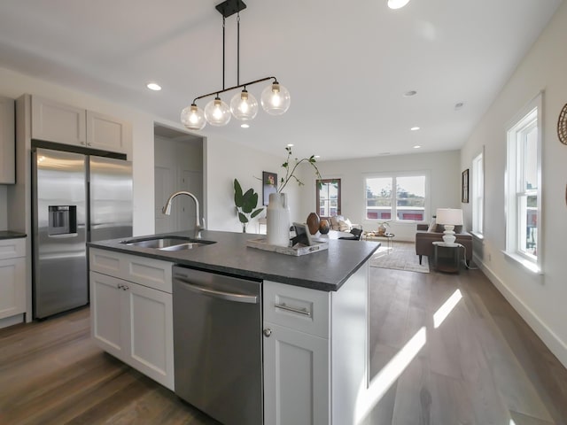 kitchen featuring a sink, stainless steel appliances, open floor plan, and dark countertops