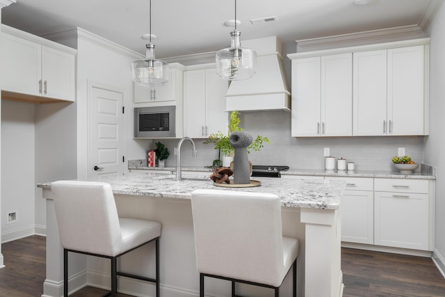 1872 Emmeline Way Unit 09, Hixson, TN 37343 - kitchen with stainless steel microwave, decorative backsplash, a kitchen island with sink, white cabinetry, and dark wood-style flooring