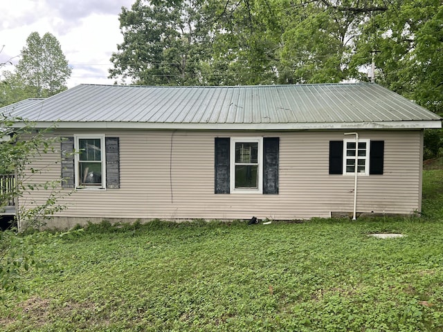 view of side of property with a lawn and metal roof