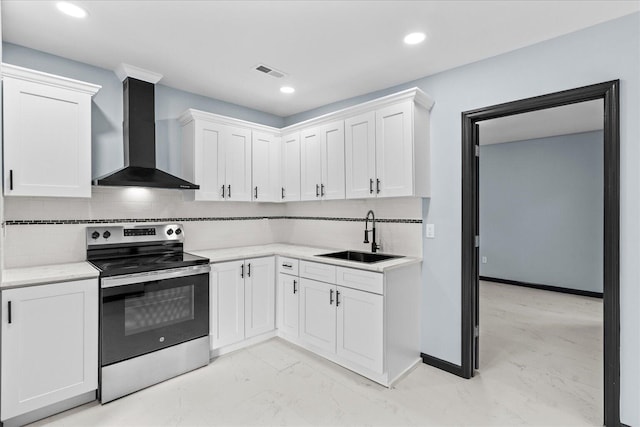 kitchen featuring a sink, wall chimney exhaust hood, light countertops, white cabinets, and electric range