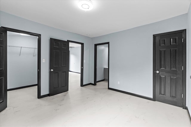 unfurnished bedroom featuring a spacious closet, baseboards, a closet, and marble finish floor