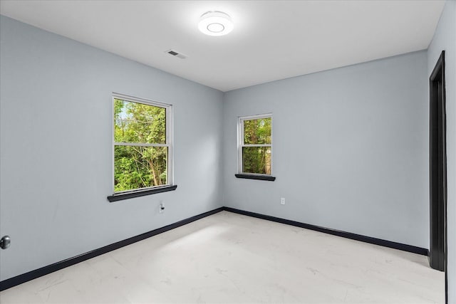 empty room featuring baseboards, marble finish floor, and visible vents
