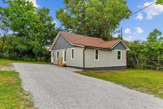 view of side of home featuring a yard, driveway, metal roof, crawl space, and entry steps