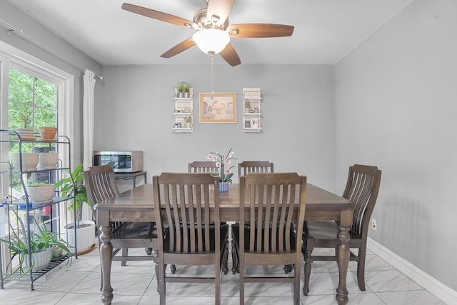 dining space featuring baseboards, a ceiling fan, and marble finish floor