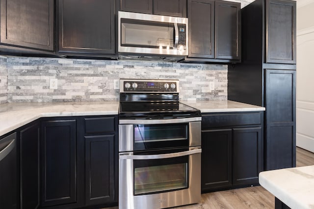 8420 Sophie Ln, Ooltewah, TN 37363 - kitchen featuring appliances with stainless steel finishes, backsplash, light wood-style flooring, and light stone counters