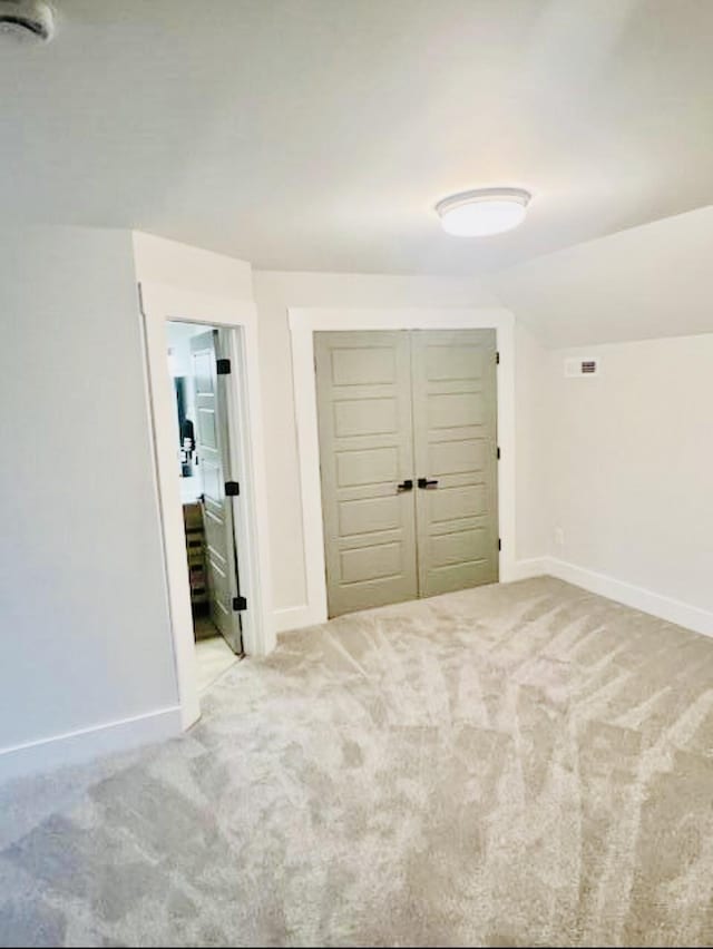 unfurnished bedroom featuring baseboards, a closet, carpet floors, and vaulted ceiling