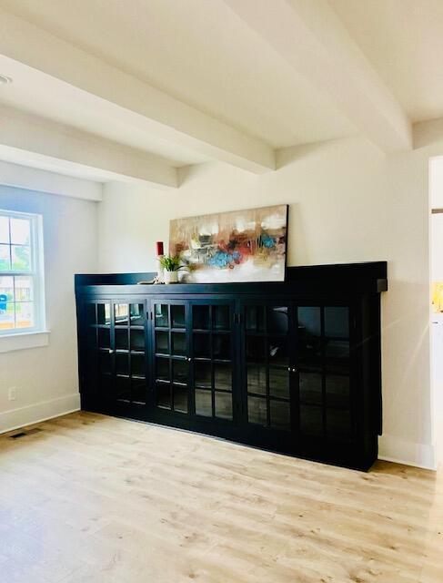 detailed view of beam ceiling, baseboards, and wood finished floors