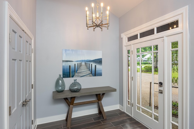foyer entrance featuring dark wood-style flooring, baseboards, a towering ceiling, and a notable chandelier