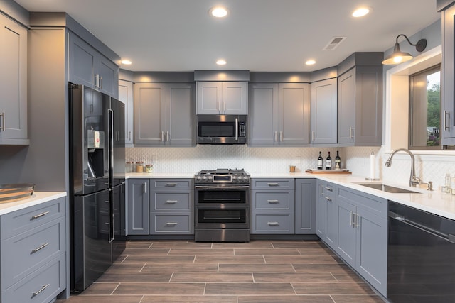 kitchen featuring recessed lighting, appliances with stainless steel finishes, gray cabinets, and a sink