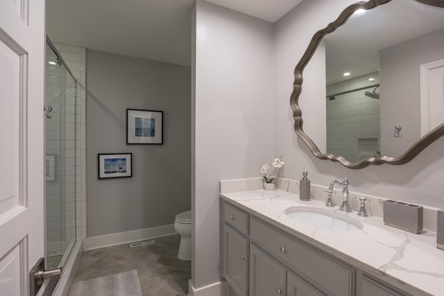 bathroom featuring toilet, baseboards, vanity, and a stall shower
