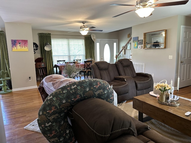 living room with ceiling fan, baseboards, wood finished floors, and stairs