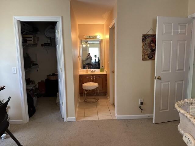 bedroom with a spacious closet, light colored carpet, a closet, a sink, and connected bathroom