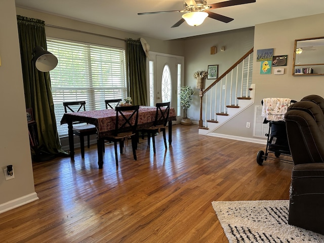 dining space with ceiling fan, stairs, wood finished floors, and baseboards
