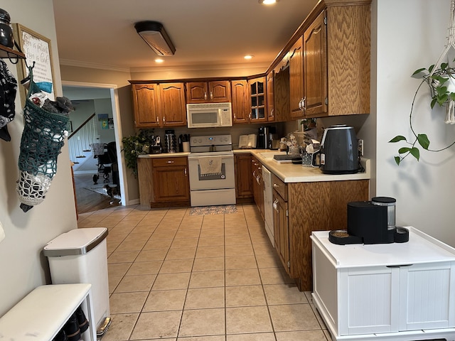 kitchen with white appliances, brown cabinetry, light tile patterned floors, light countertops, and crown molding