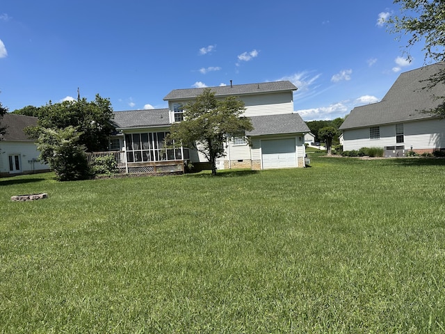 rear view of house with a garage, a sunroom, and a yard