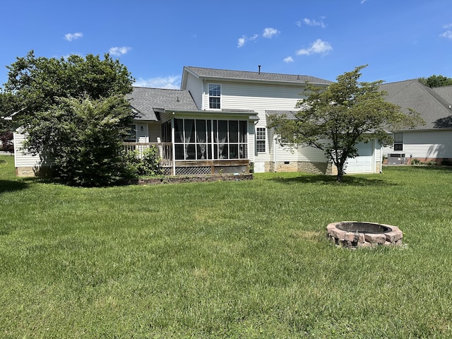 rear view of house with a sunroom, an outdoor fire pit, a lawn, and crawl space