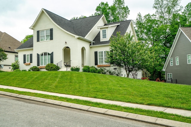 view of front facade with a shingled roof, a front lawn, and brick siding