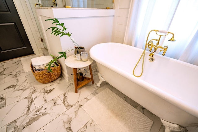 bathroom with marble look tile flooring, a freestanding tub, and a walk in shower