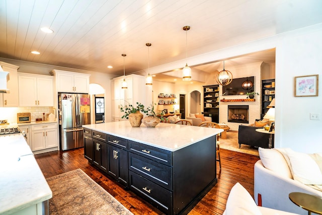 kitchen with freestanding refrigerator, dark cabinets, arched walkways, open floor plan, and recessed lighting
