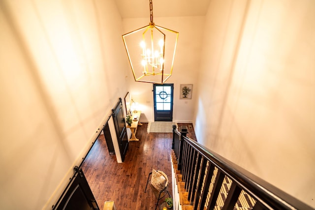 entryway with dark wood-type flooring, a chandelier, a towering ceiling, and baseboards