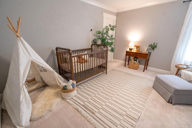 carpeted bedroom featuring baseboards, crown molding, and a nursery area