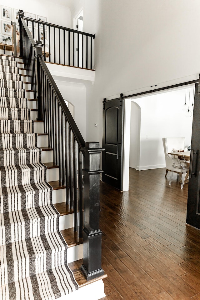 9405 Peppy Branch Trl, Apison, TN 37302 - staircase featuring a barn door, hardwood / wood-style floors, a towering ceiling, and baseboards