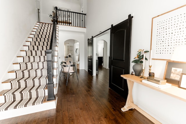 9405 Peppy Branch Trl, Apison, TN 37302 - entryway with arched walkways, dark wood-style floors, a barn door, and a towering ceiling