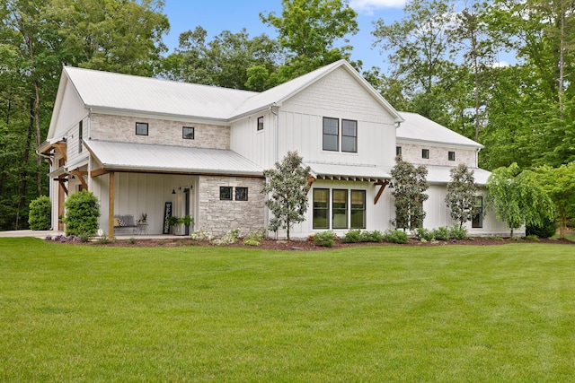 back of property featuring board and batten siding, a lawn, and stone siding