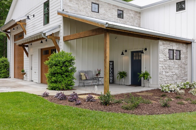 doorway to property featuring board and batten siding, stone siding, and covered porch