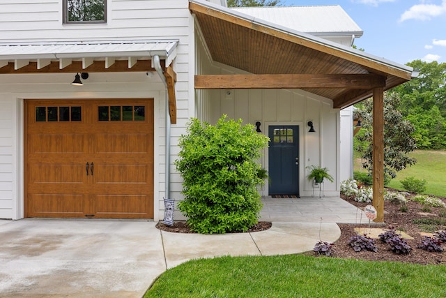 entrance to property featuring concrete driveway and an attached garage