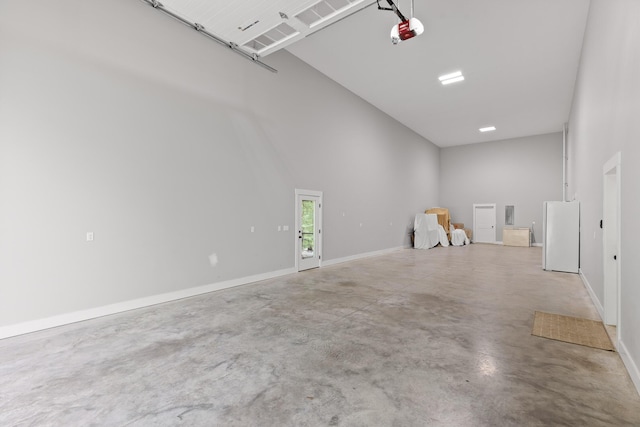 garage featuring freestanding refrigerator, a garage door opener, and baseboards