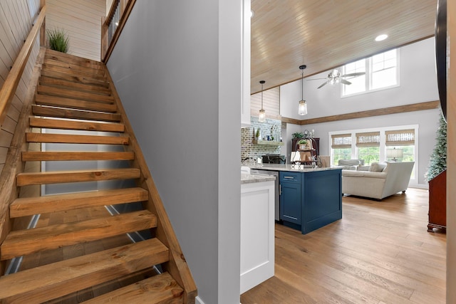 stairway with a high ceiling, ceiling fan, and wood finished floors