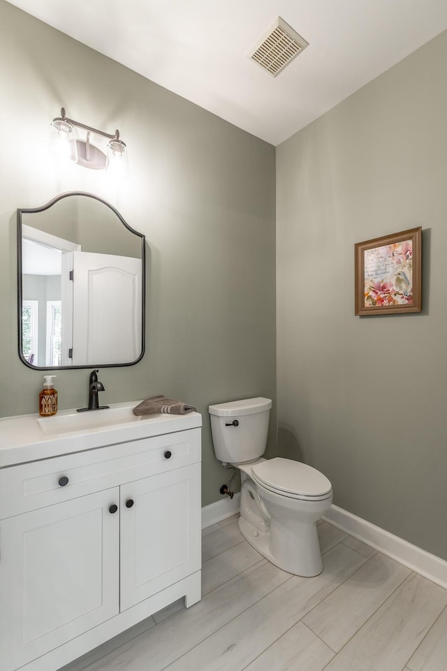 bathroom featuring baseboards, toilet, and vanity