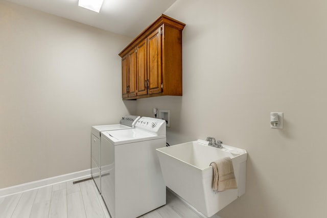 washroom featuring washing machine and dryer, cabinet space, and baseboards