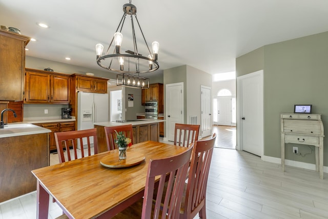 dining space with a chandelier, light wood-style floors, baseboards, and recessed lighting