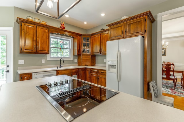 kitchen featuring white appliances, a sink, light countertops, brown cabinetry, and recessed lighting