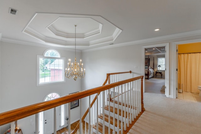 corridor with healthy amount of natural light, an upstairs landing, carpet floors, a chandelier, and crown molding