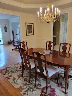 dining space featuring ornamental molding, wood finished floors, a chandelier, and a raised ceiling
