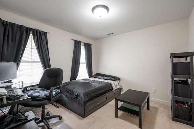 bedroom with a desk and light colored carpet