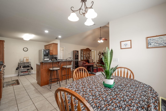 dining room featuring a ceiling fan, light tile patterned floors, vaulted ceiling, a chandelier, and baseboards