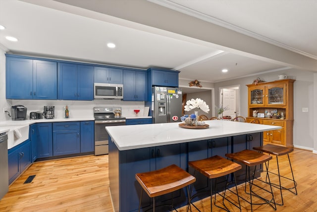 1123 Ridgeleigh Cir, Dalton, GA 30720 - kitchen featuring appliances with stainless steel finishes, blue cabinetry, a kitchen breakfast bar, light wood-type flooring, and recessed lighting