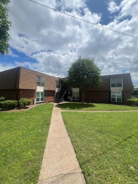 view of front of house with brick siding and a front lawn