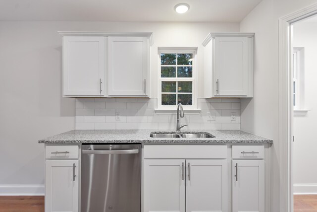 kitchen with dishwasher, a sink, backsplash, and baseboards