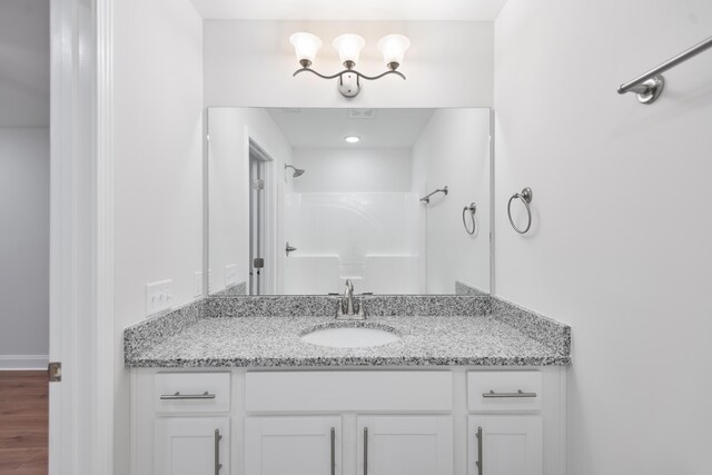 bathroom featuring a shower, vanity, and wood finished floors
