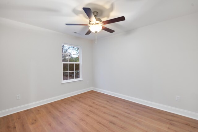 spare room with light wood finished floors, a ceiling fan, and baseboards