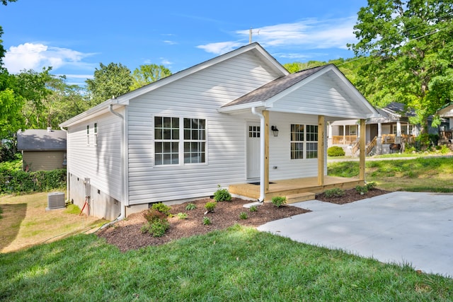 view of front facade featuring a porch, a front yard, and central AC