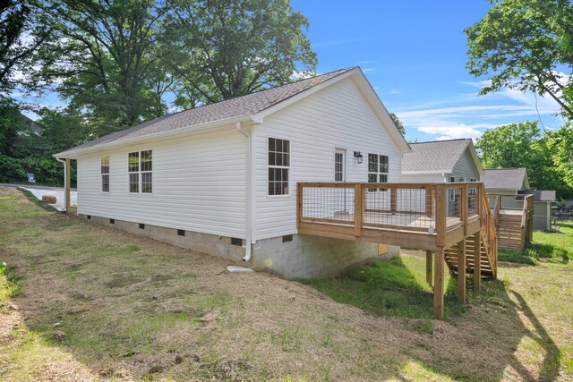 view of property exterior with crawl space, a wooden deck, roof with shingles, and a lawn