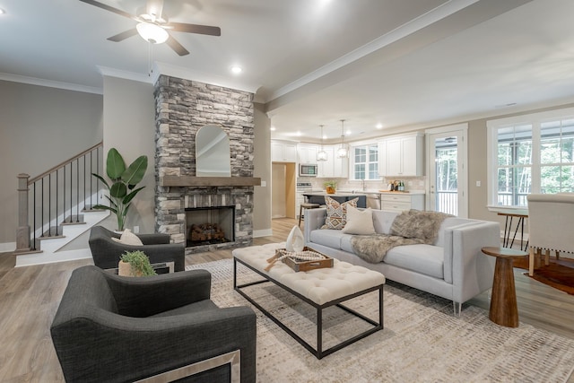 11570 Armstrong Rd, Soddy Daisy, TN 37379 - living room with ornamental molding, light wood finished floors, ceiling fan, a stone fireplace, and stairs